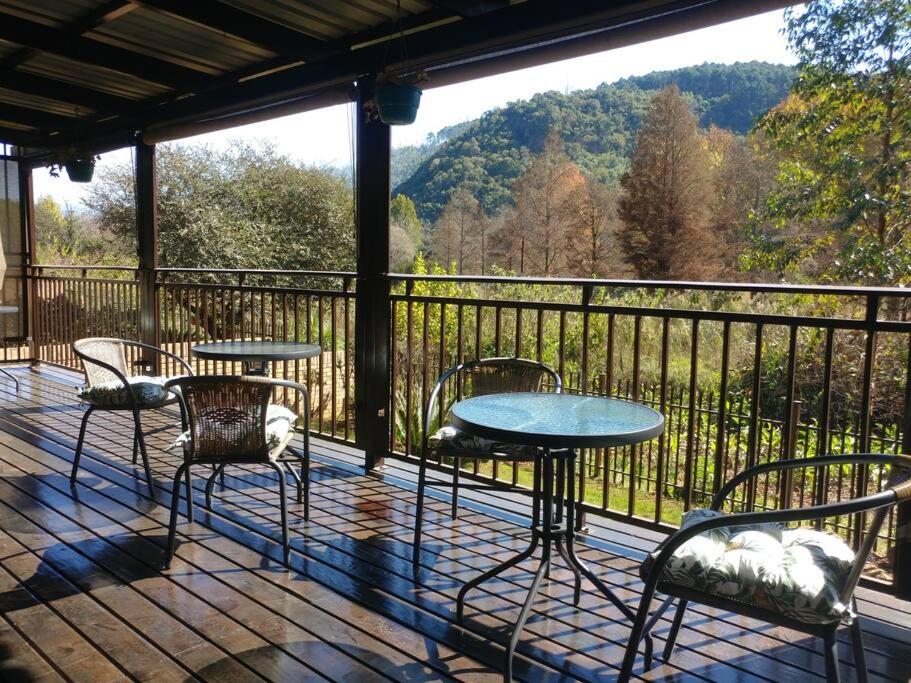 a patio with tables and chairs on a deck with a view at Ebeneezer Self-Catering Guesthouse in the Lowveld in Sabie