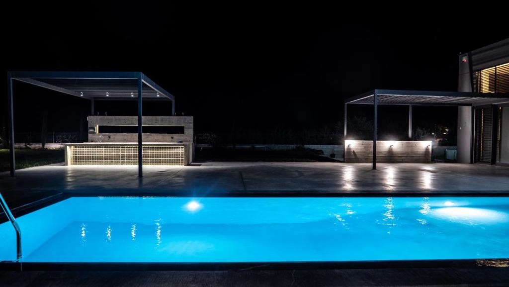 uma piscina à noite com um pavilhão em Olive suite, guesthouse by Villa Elia em Markopoulon