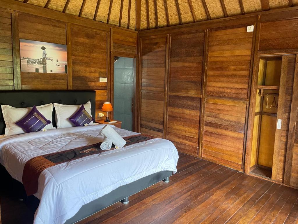 a bedroom with a bed in a room with wooden walls at Mangrove Beach Hut in Nusa Lembongan