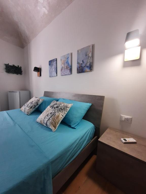 een slaapkamer met een bed met blauwe lakens en kussens bij TURISMO EGADI - CHARME in Favignana