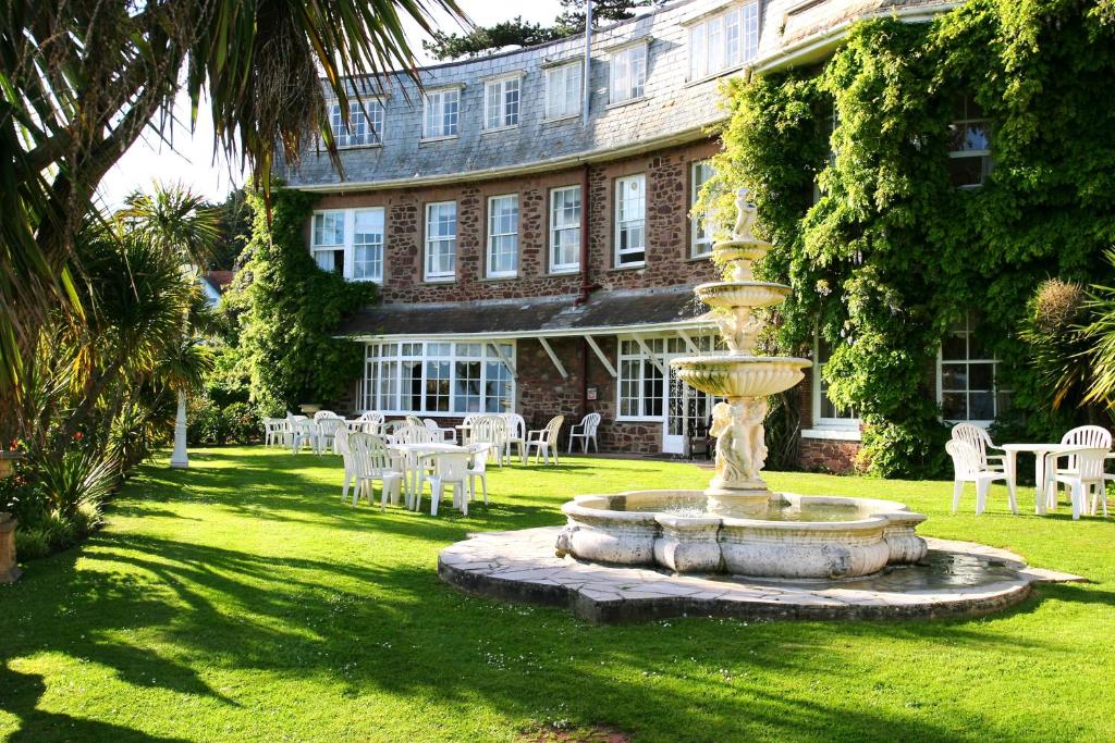 a fountain in front of a building with tables and chairs at Livermead House Hotel in Torquay
