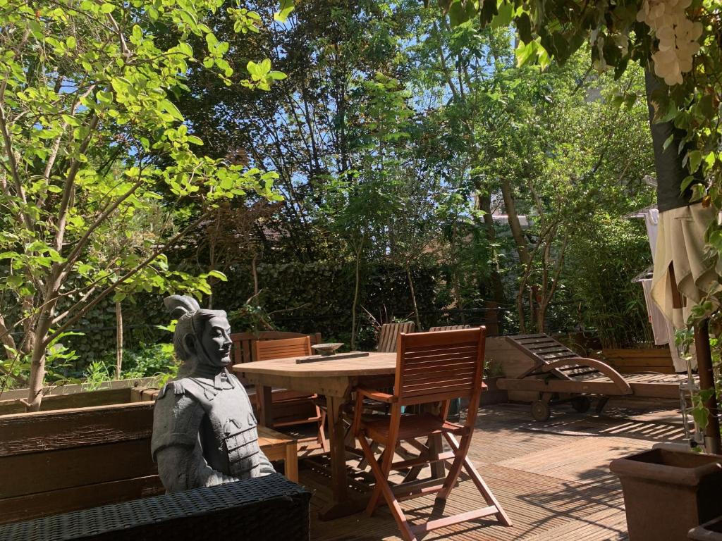 une statue d'une femme assise à une table dans un jardin dans l'établissement Paris Central Design Jardin & Terrasse privé, à Paris