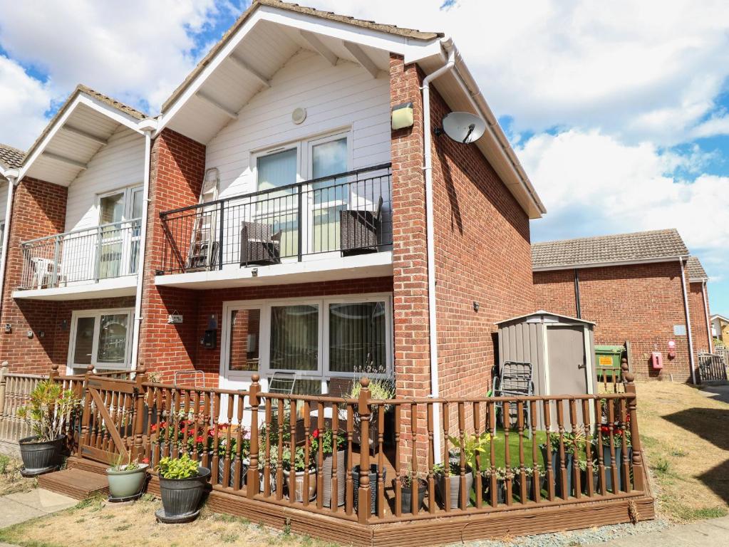 a brick house with a wooden fence in front of it at 30 The Waterside Holiday Park in Lowestoft