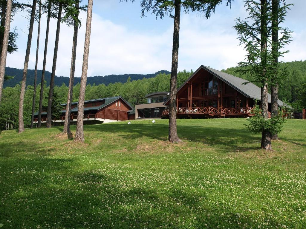 a large building with trees in front of it at Log Hotel Larch Lake Kanayama in Minamifurano