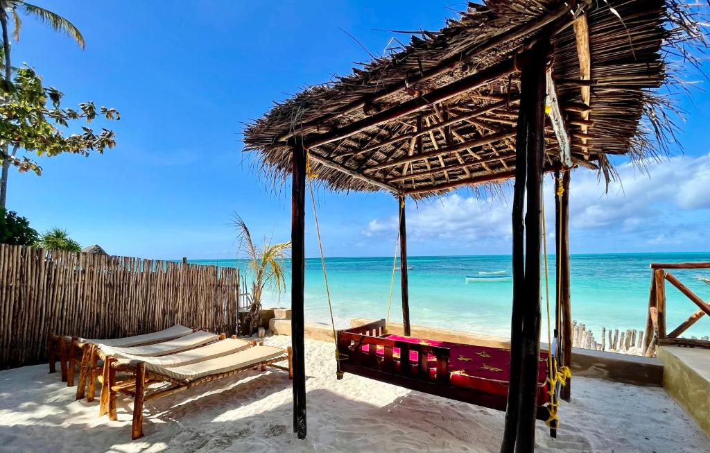 a beach with a bed and an umbrella on the sand at Equalia Rose Hotel in Jambiani