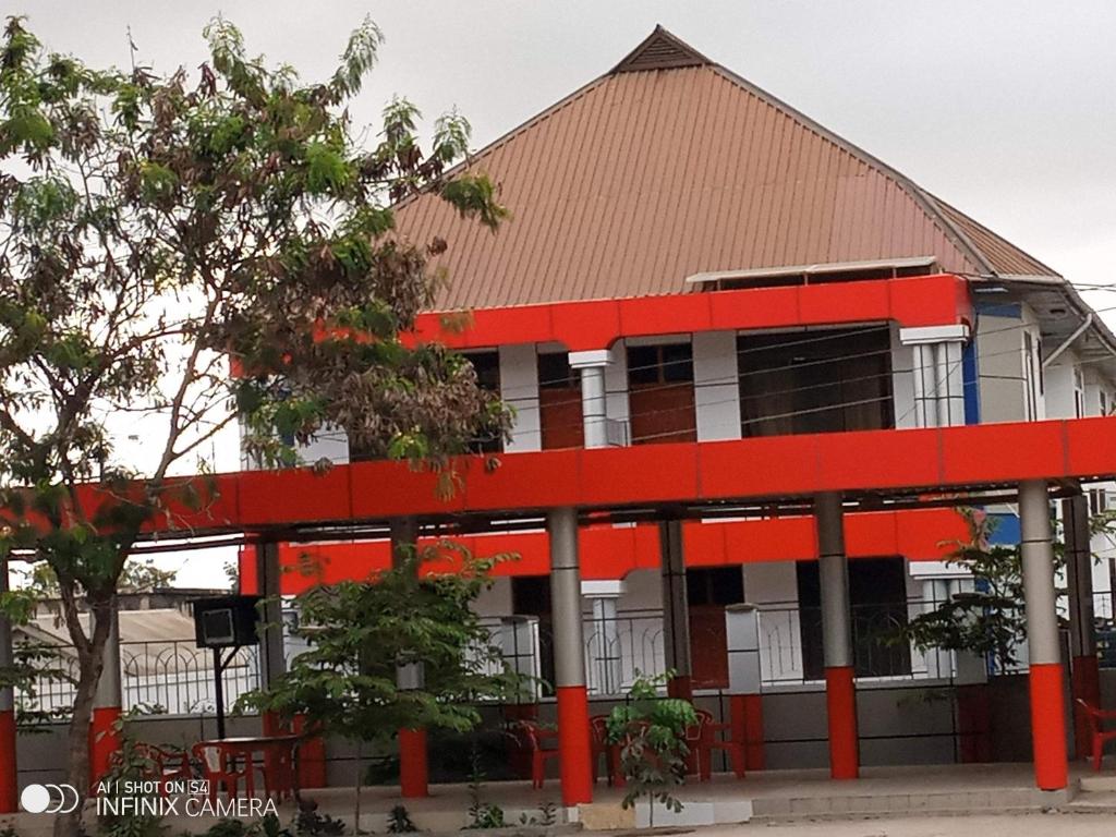 an orange and white building with trees in front of it at Masami lodge boma ng'ombe in Tuvaila