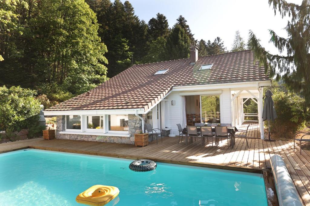 une maison avec une piscine devant une maison dans l'établissement LE CHALET BLANC - JACUZZI / PISCINE / SAUNA, à Gérardmer