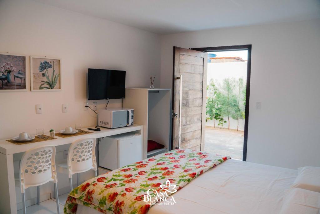 Schlafzimmer mit einem Bett, einem Schreibtisch und einem TV in der Unterkunft Casa Blanca in Galinhos