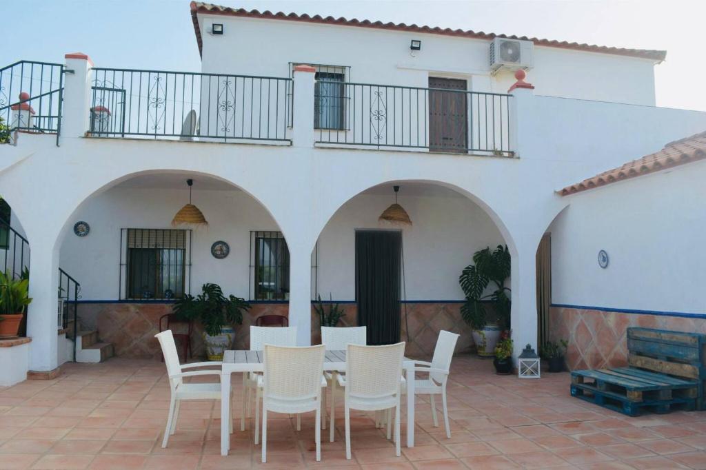 Un patio con una mesa y sillas frente a un edificio. en Casa Con Piscina Y Pista De Tenis, en Alhaurín de la Torre