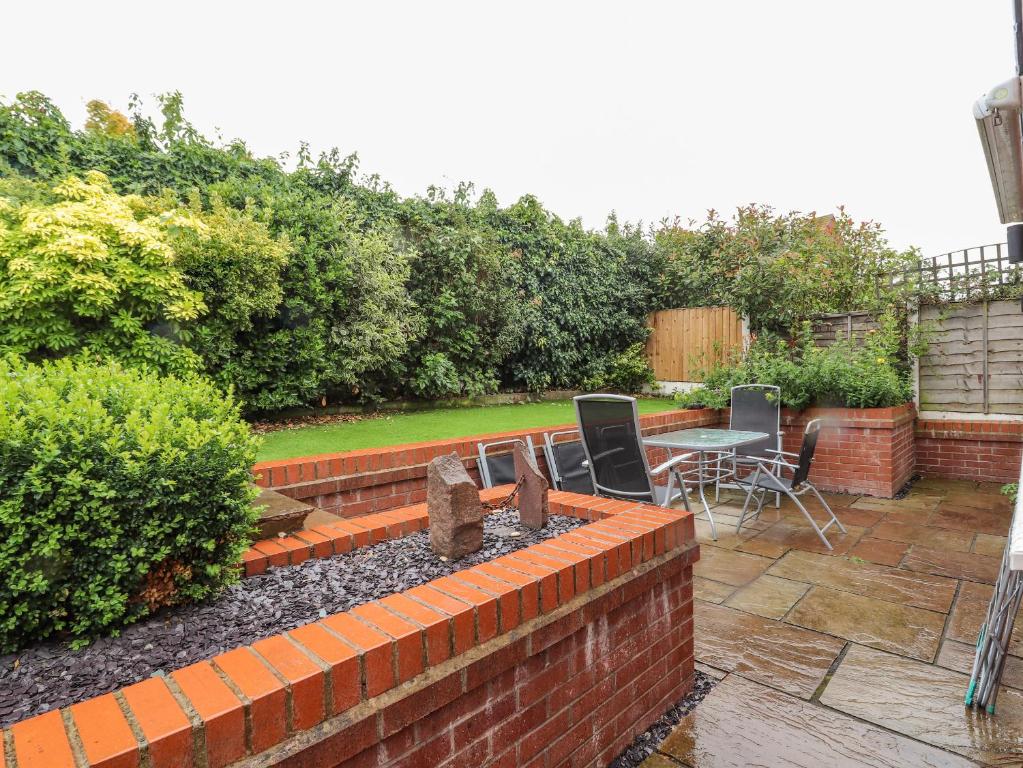 a brick retaining wall with a table and chairs in a garden at Crummock in Frodsham