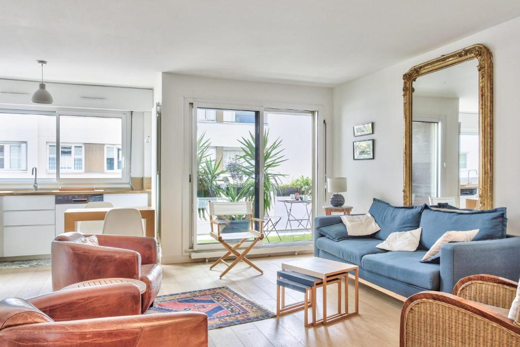 un salon avec un canapé bleu et un miroir dans l'établissement Appartement Charlys avec sa terrasse - Welkeys, à Paris