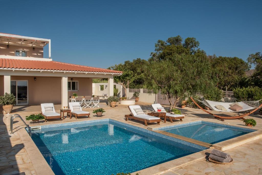 uma piscina com cadeiras e uma casa em Filothei Beach House with pool em Kalamaki