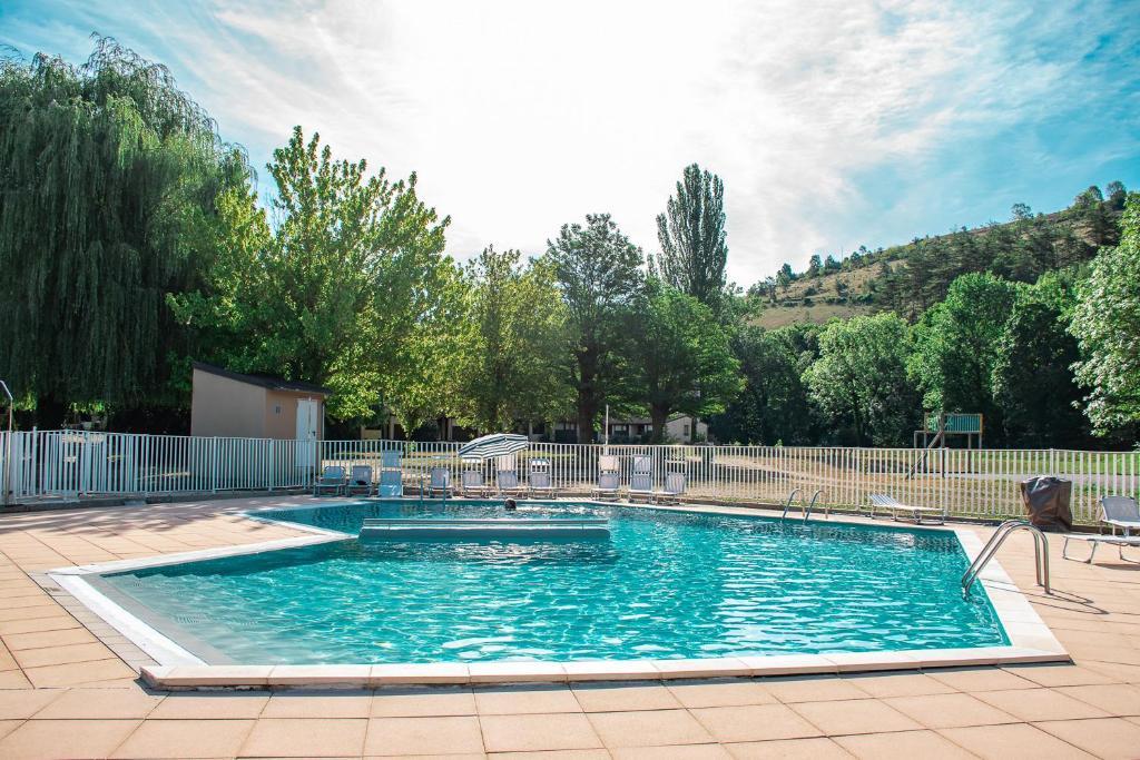 uma grande piscina com cadeiras num quintal em Village Gévaudan Aubrac em Marvejols