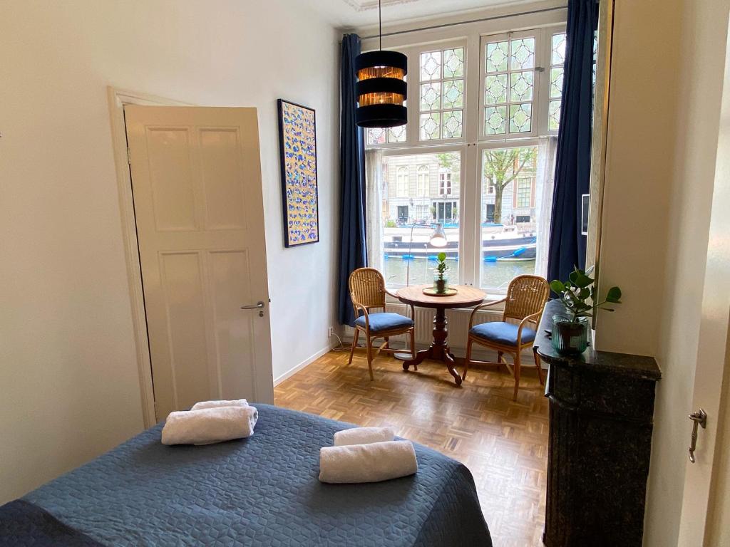 ein Schlafzimmer mit einem Bett und einem Tisch und einem Fenster in der Unterkunft Canal Hideaway in Amsterdam