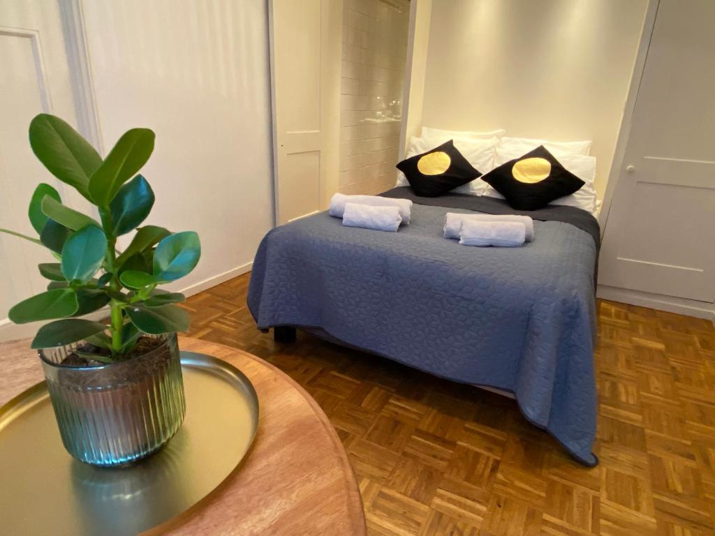 ein Schlafzimmer mit einem blauen Bett mit Kissen und einer Pflanze in der Unterkunft Canal Hideaway in Amsterdam