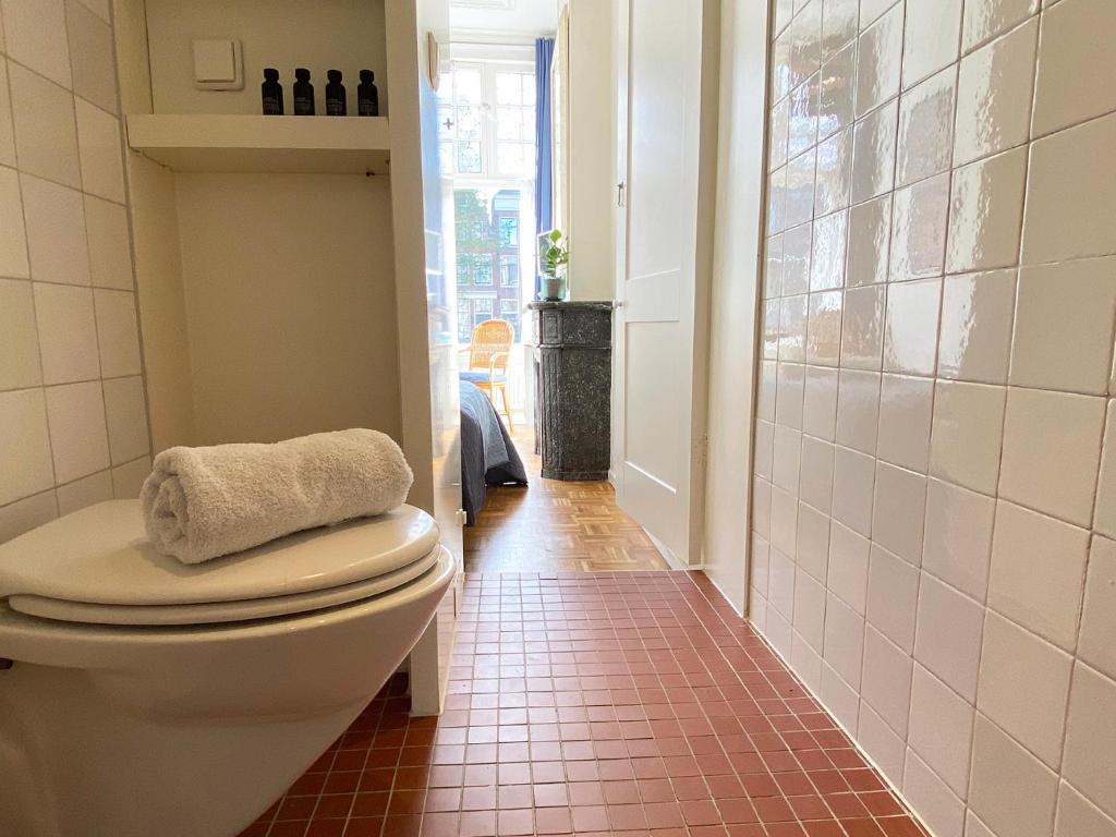 ein Badezimmer mit Toilette und Fliesenboden in der Unterkunft Canal Hideaway in Amsterdam