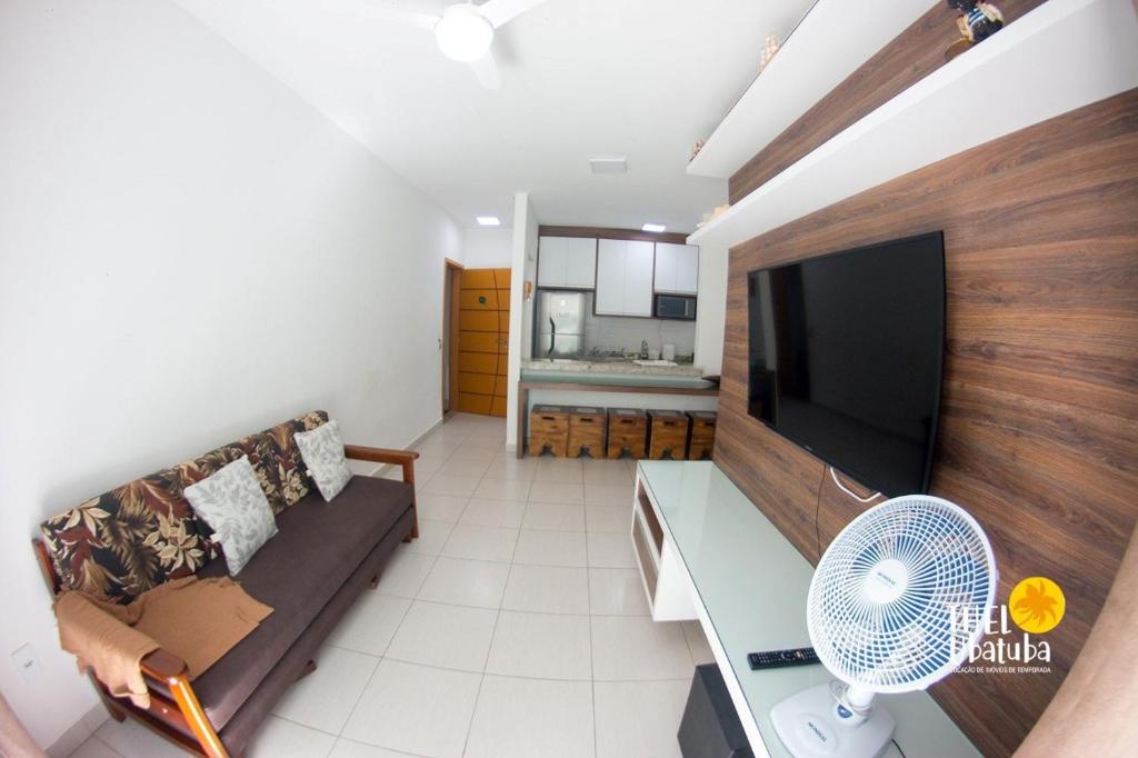 uma sala de estar com um sofá e uma televisão de ecrã plano em Thel Ubatuba - Apto 48/A, Saint Martin em Ubatuba