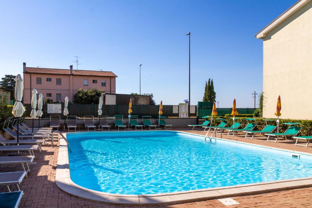 a large swimming pool with chairs and a building at Isola Rossa Appartamento 1pt in Alberese