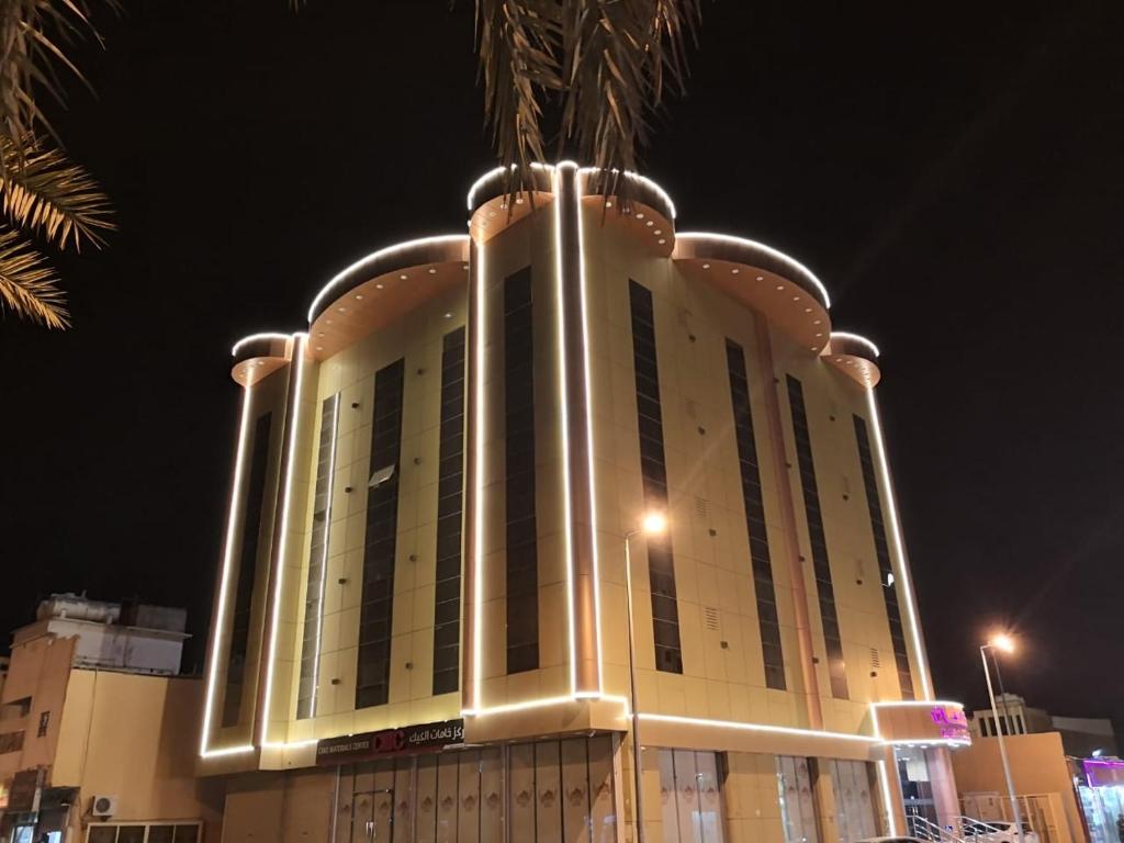 ein großes Gebäude mit Lichtern in der Nacht in der Unterkunft شقق البحر الازرق المخدومة in Bisha