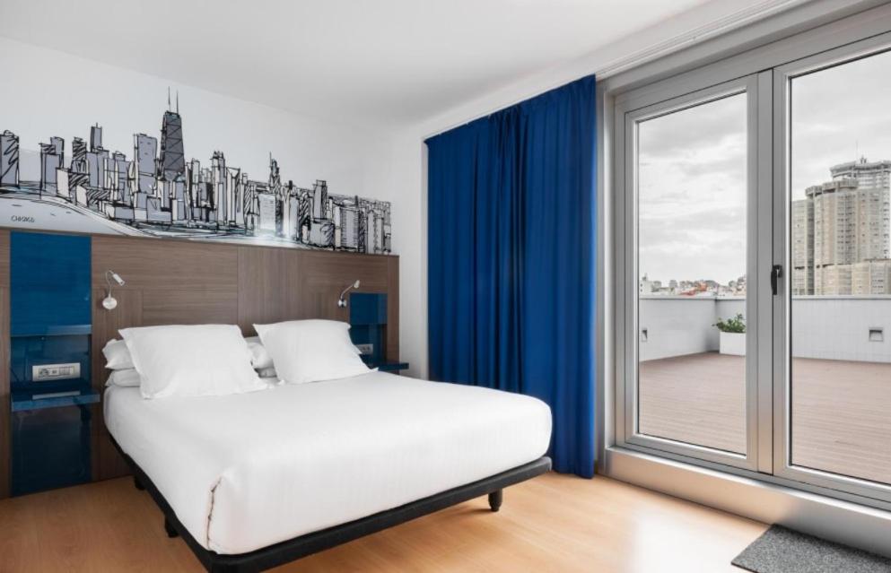 a bedroom with a white bed and a large window at Eurostars Blue Coruña in A Coruña