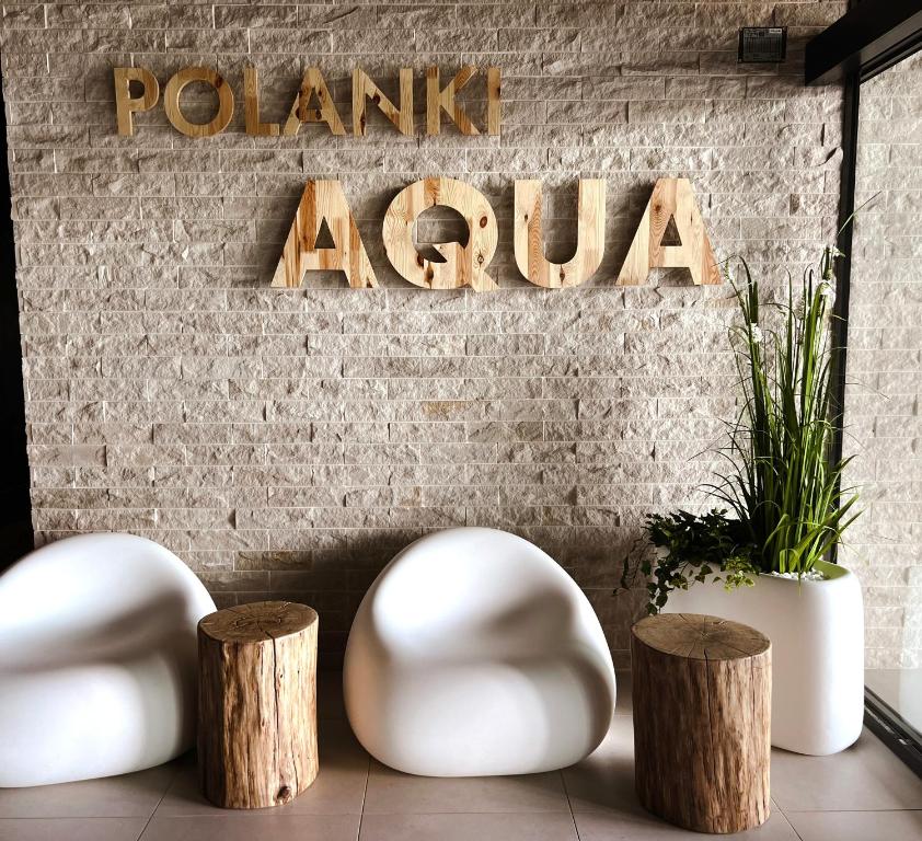 Cette chambre dispose de deux chaises blanches et de tabourets en bois. dans l'établissement Apartament Polanki Aqua A408, à Kołobrzeg