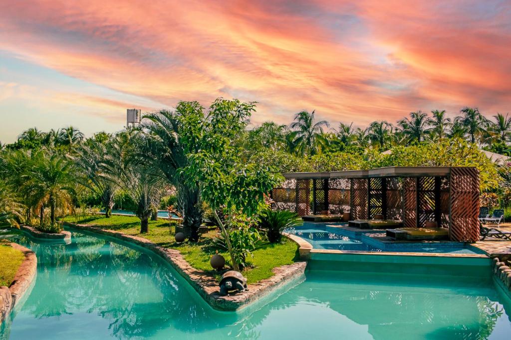 um resort com piscina e palmeiras em Hot Beach Resort em Olímpia