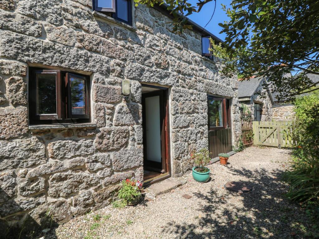 ein Steinhaus mit einer Tür und einem Hof in der Unterkunft Lower Rissick Cottage in Penzance