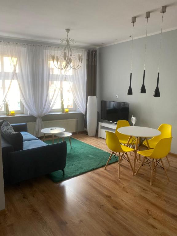 a living room with a couch and tables and yellow chairs at Apartament Jedności in Zielona Góra