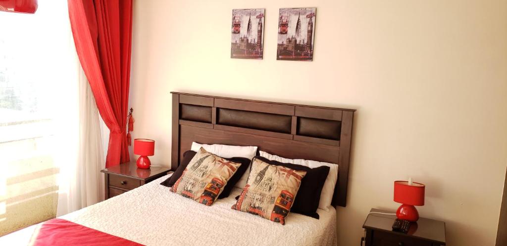 een slaapkamer met een bed met 2 rode lampen en rode gordijnen bij Arriendo departamentos PA 6 y 7 in Santiago