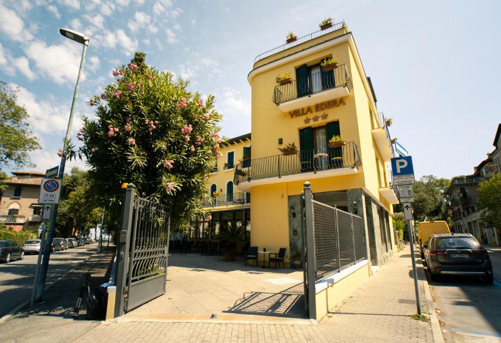 un edificio giallo in una strada di città con cancello di Hotel Villa Edera a Lido di Venezia