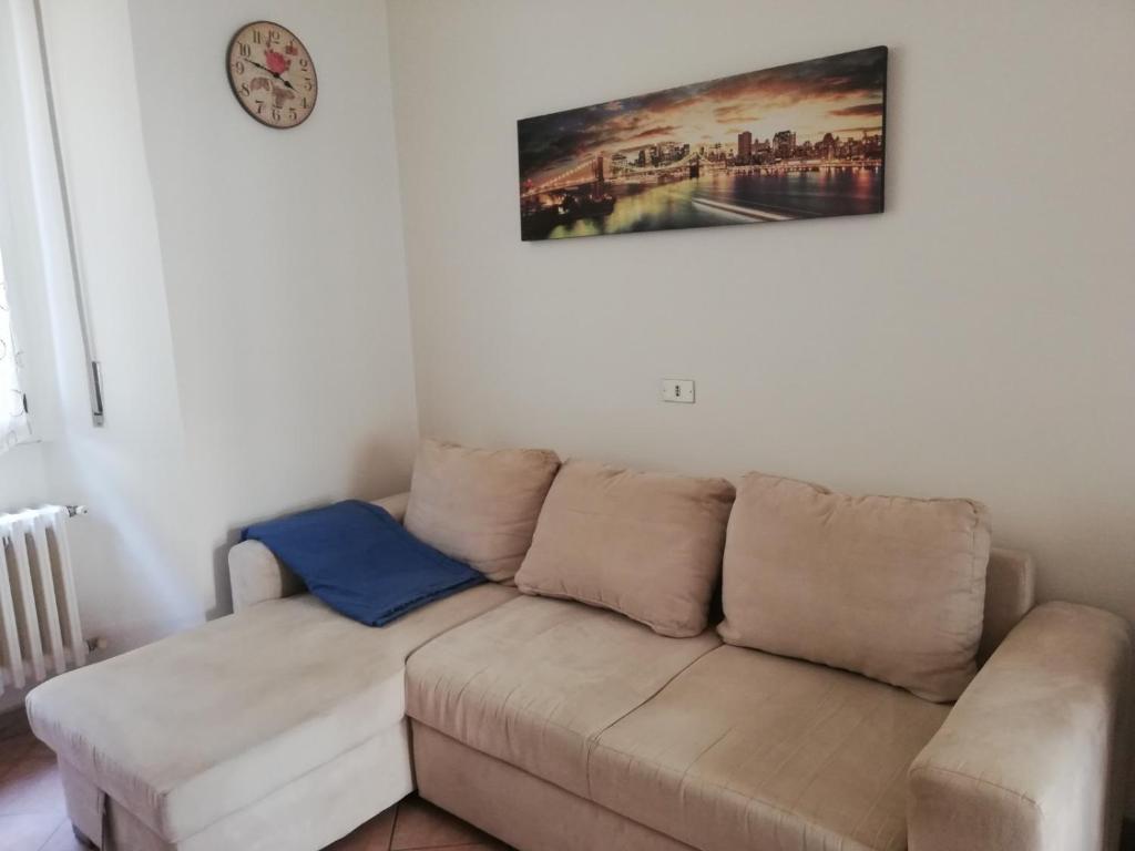 un divano in soggiorno con un orologio sul muro di Appartamento 3 del Vecchio Convento a Orino