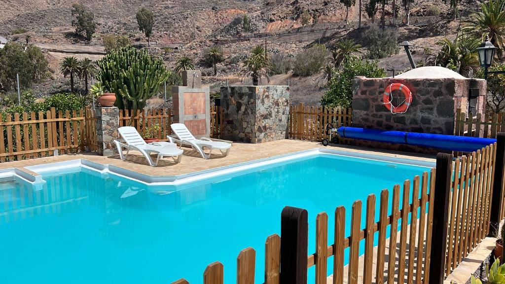 - une piscine avec 2 chaises à côté d'une clôture dans l'établissement casa rural LA LIMERA con piscina privada, à Santa Lucía