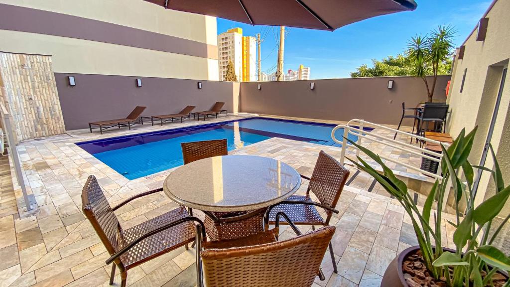 un patio con mesa, sillas y piscina en Comfort Hotel Bauru en Bauru