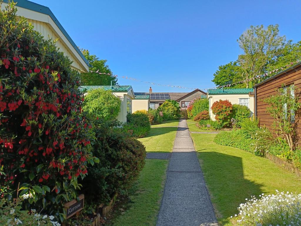 a walkway through a garden with flowers and bushes at Rivermead Holidays in Saint Breward