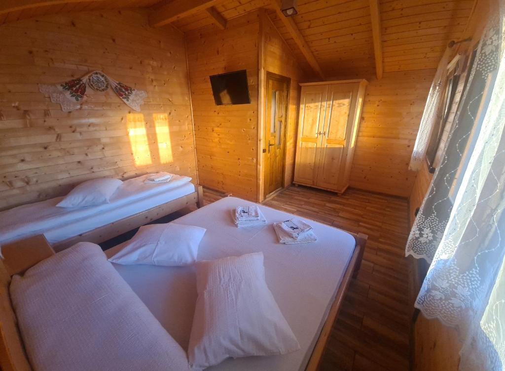 a room with two beds in a wooden cabin at Pensiunea Anisoara in Chişcău