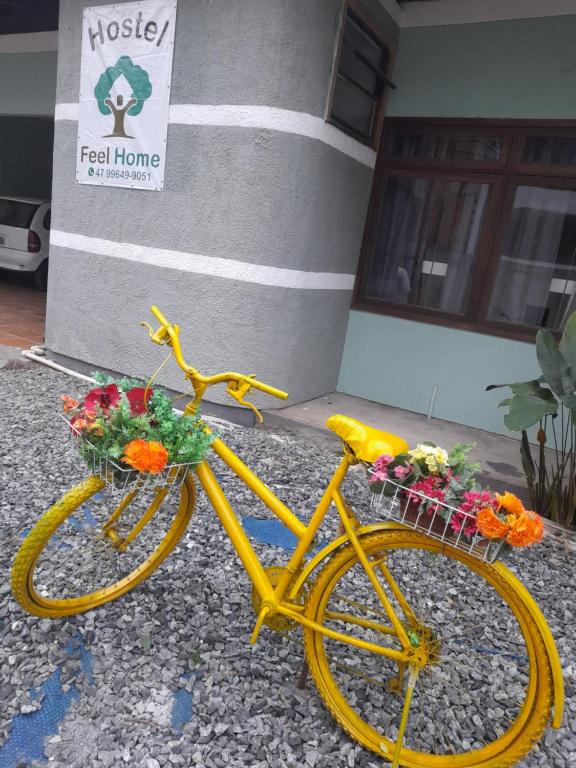 una bicicleta amarilla con flores en cestas estacionadas frente a un edificio en Hostel Feel Home, en Blumenau