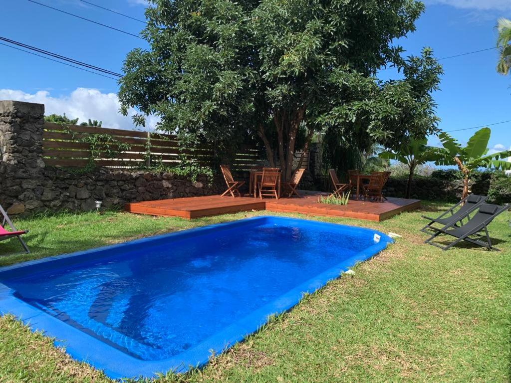 uma piscina azul num quintal com cadeiras e uma árvore em Appartement 2 avec wifi em Ravine des Cabris