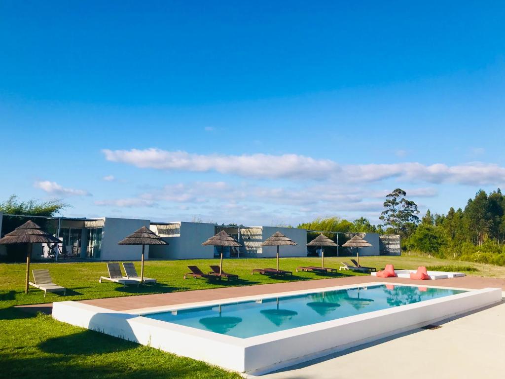 a pool at a resort with chairs and umbrellas at Pe no Monte in São Teotónio