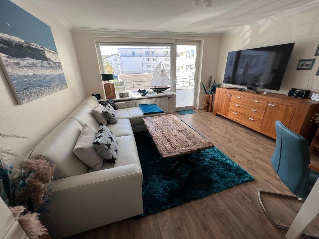 ein Wohnzimmer mit einem weißen Sofa und einem TV in der Unterkunft Luxus-Loft-Sylt Haus Dünenburg in Westerland