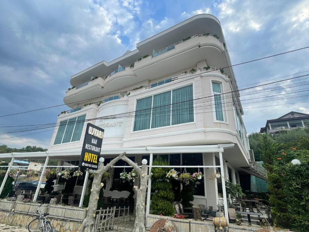 HOTEL UJVARA في Belsh-Qendra: مبنى ابيض امامه لافته