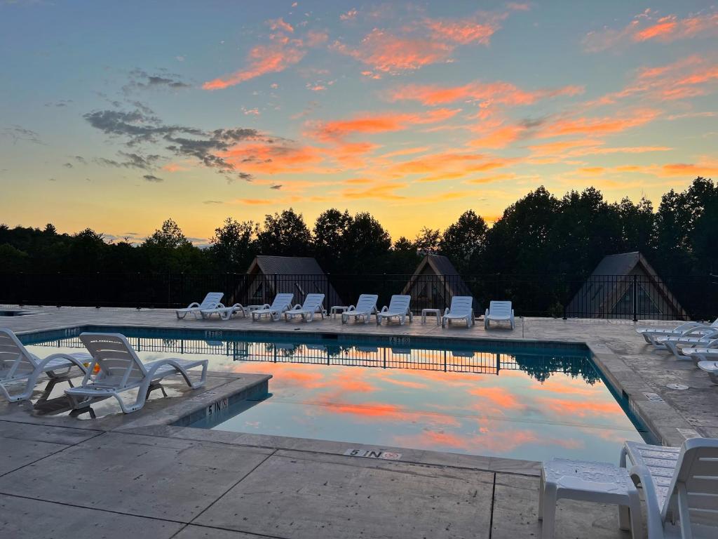 a swimming pool with lounge chairs and a sunset at SKYLARANNA Resort & SPA in Hendersonville
