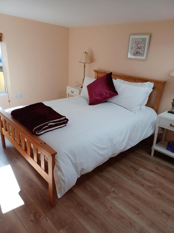 um quarto com uma cama grande com lençóis brancos e almofadas vermelhas em Kents guesthouse accommodation em Kilmacthomas