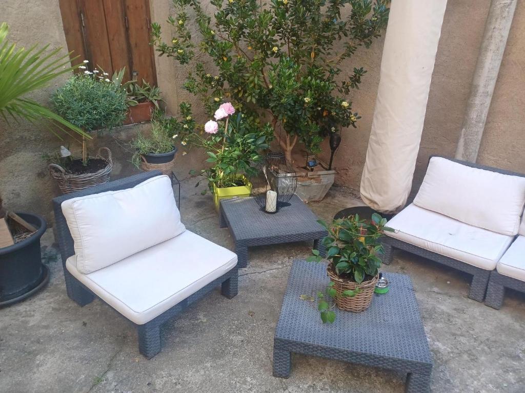 two chairs and a table with potted plants on a patio at Chambre d'hôte Au Jardin Le clos des vins d'Anges in Saint-Pierre-des-Champs