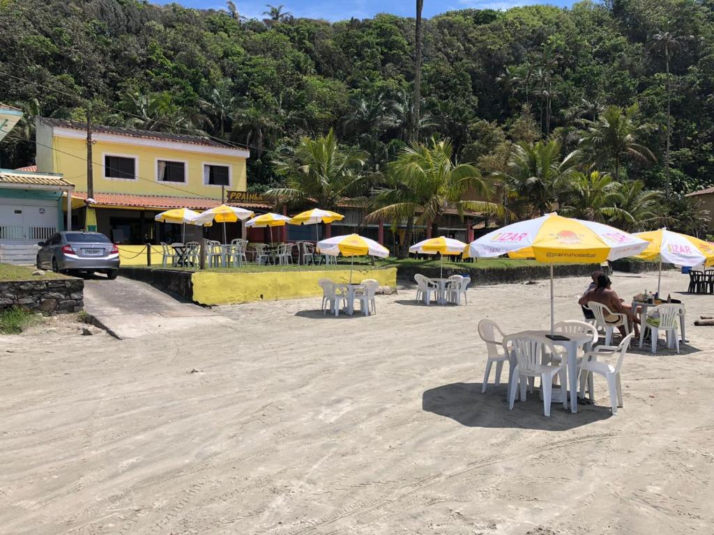 un grupo de mesas y sillas con sombrillas en la playa en Prainha Pousada - Bar e Restaurante, en Itanhaém