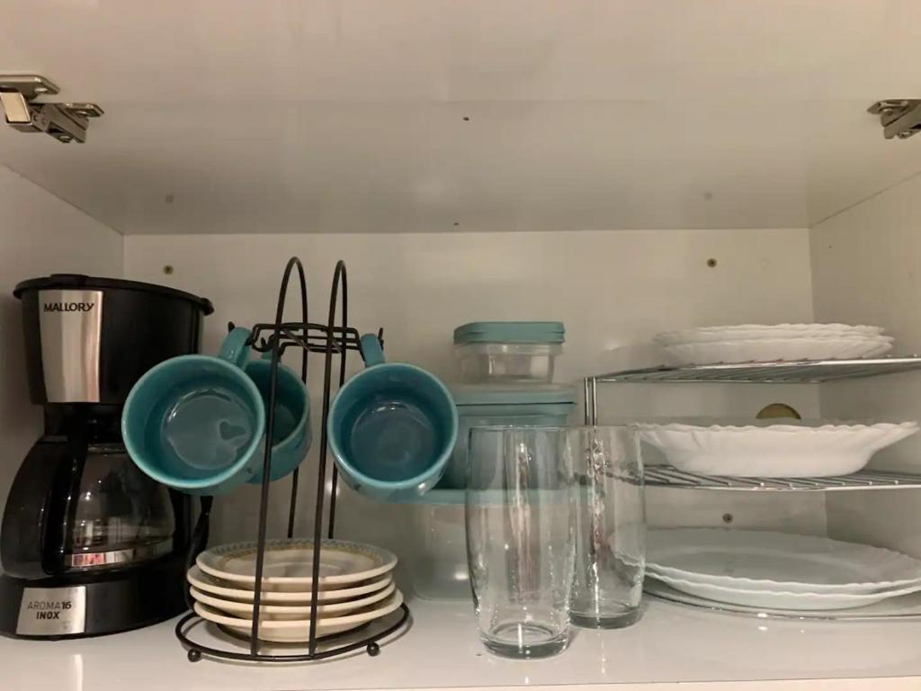 a kitchen with plates and utensils on a shelf at Studio aconchegante em Barra Mansa in Barra Mansa