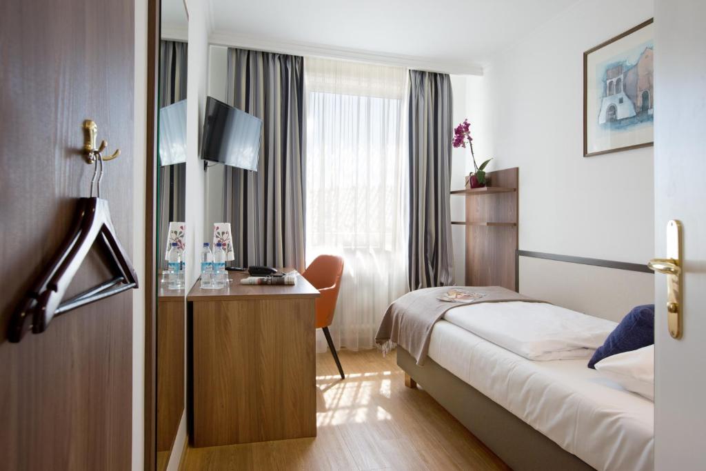 ミュンヘンにあるHotel Aurbacher Hof GmbHのベッドとデスクが備わるホテルルームです。