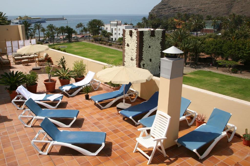 a group of chairs and umbrellas on a patio at Hotel Torre Del Conde in San Sebastián de la Gomera