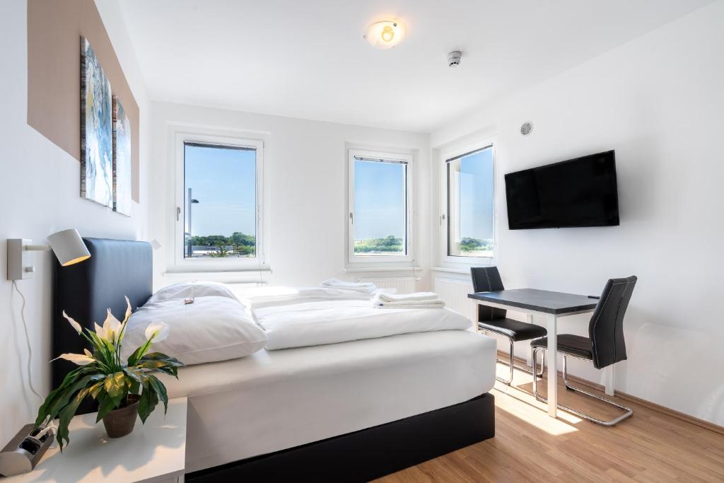 a white bedroom with a bed and a desk at FeelGood Apartments LakeLiving inklusive Garagenplatz in Vienna