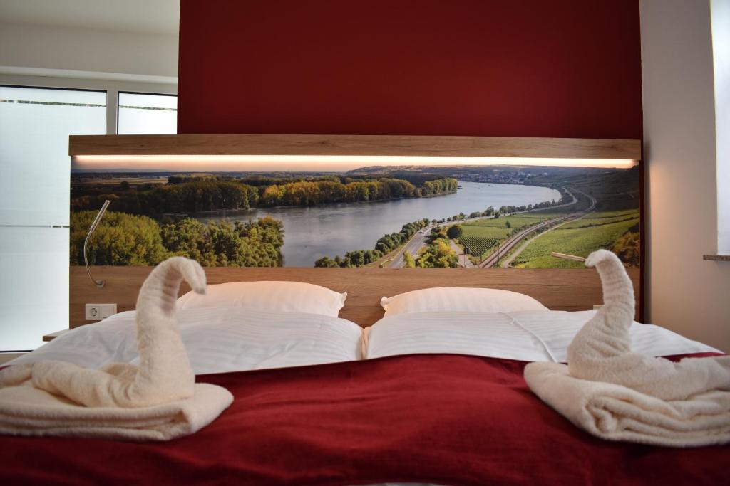 a bed with swan towels on it with a picture on the wall at Weingut Lindenhof Kröhler 