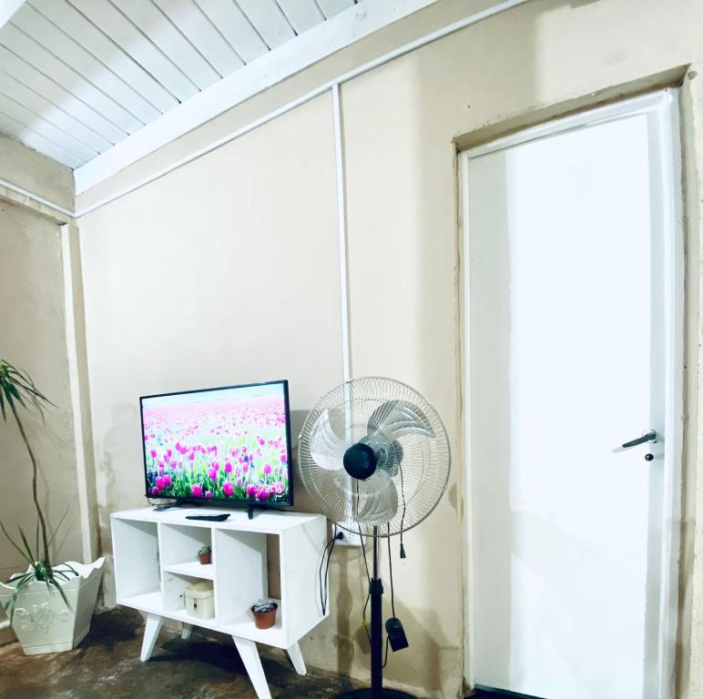 a room with a fan and a computer on a white cabinet at Cayetana in Puerto Iguazú